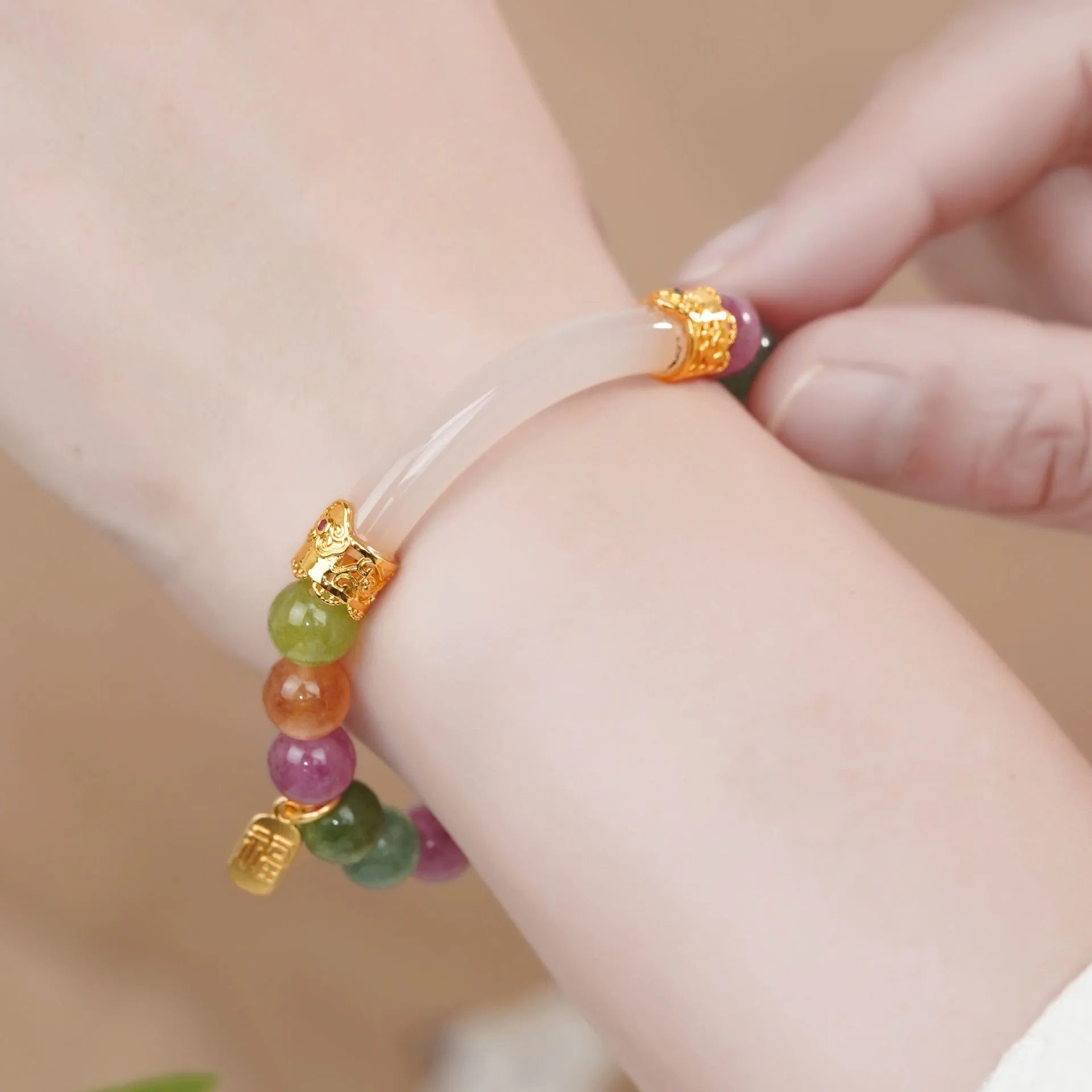 Rainbow coloured electroplated tourmaline half bracelet for women on a wrist.