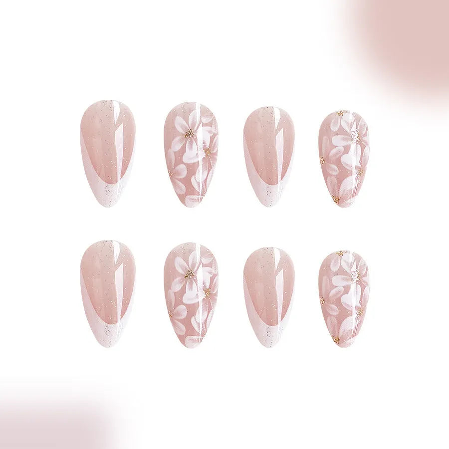 Short almond shaped faux nails with French manicure style and glittery pink flower design.