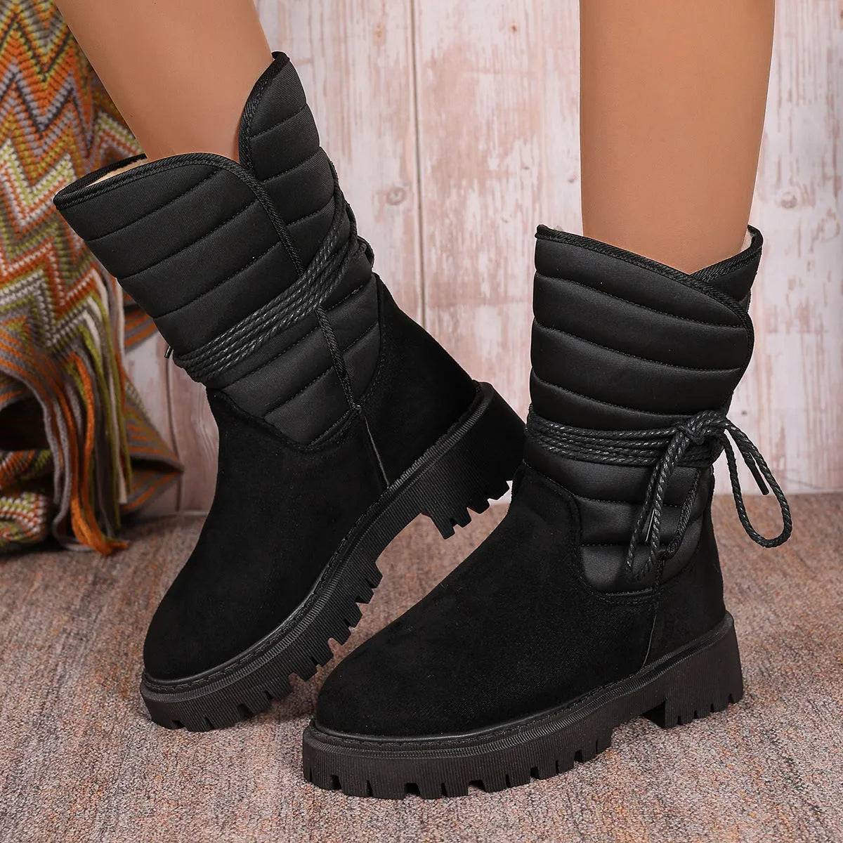 Women's black suede snow boots with chunky heel and lace-up design, shown on a foot.