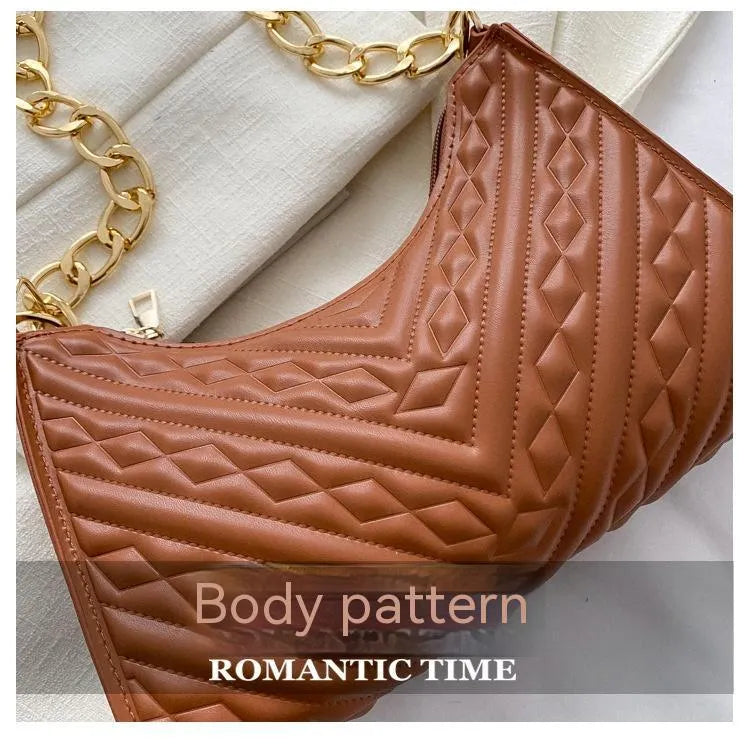 Vertical square brown PU shoulder bag with chain strap and soft handle on a table