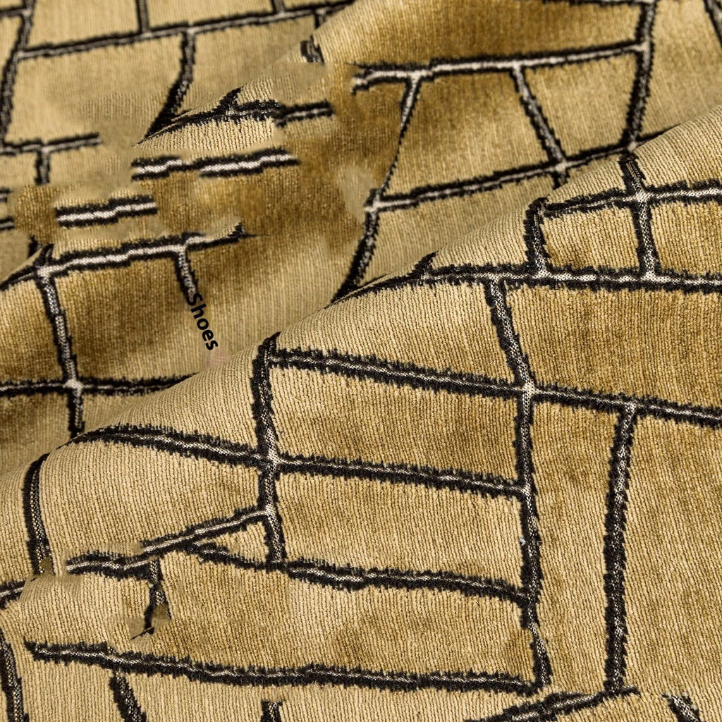 Gold geometric pattern on a velvet square cushion and a rectangular waist pillow against a sofa.