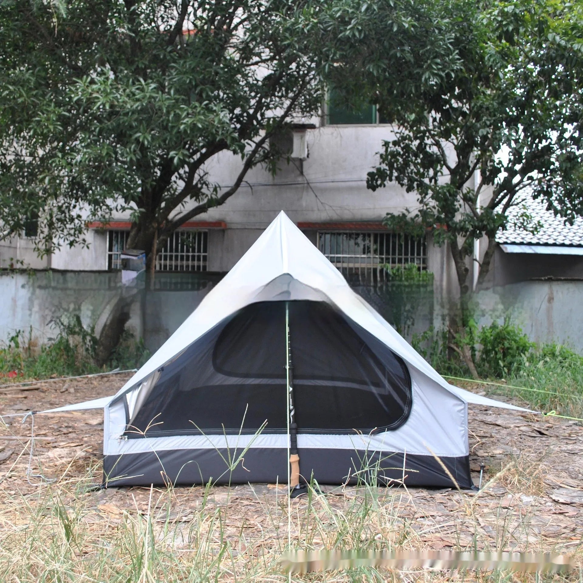 Brown or white A-line hiking tent without poles, supported by hiking canes