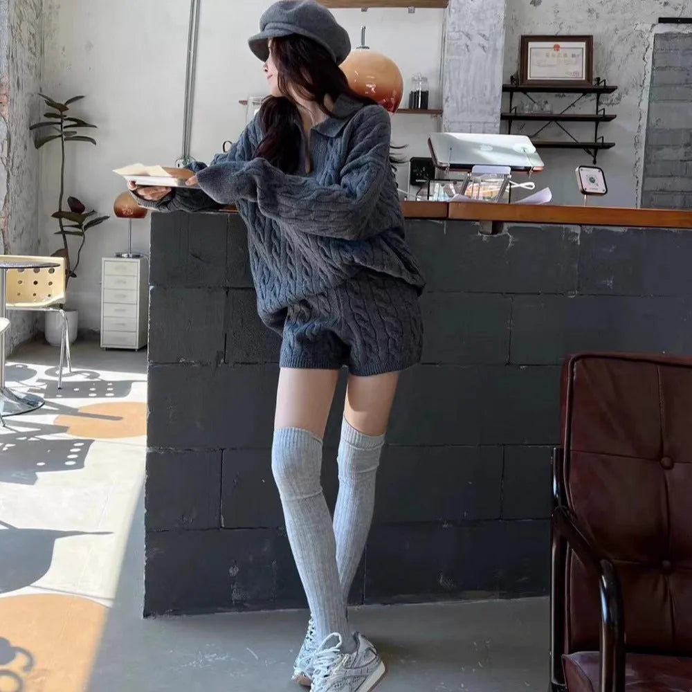Women's creamy-white knitted suit set with cable knit pattern, long sleeve top, and elastic waist shorts.