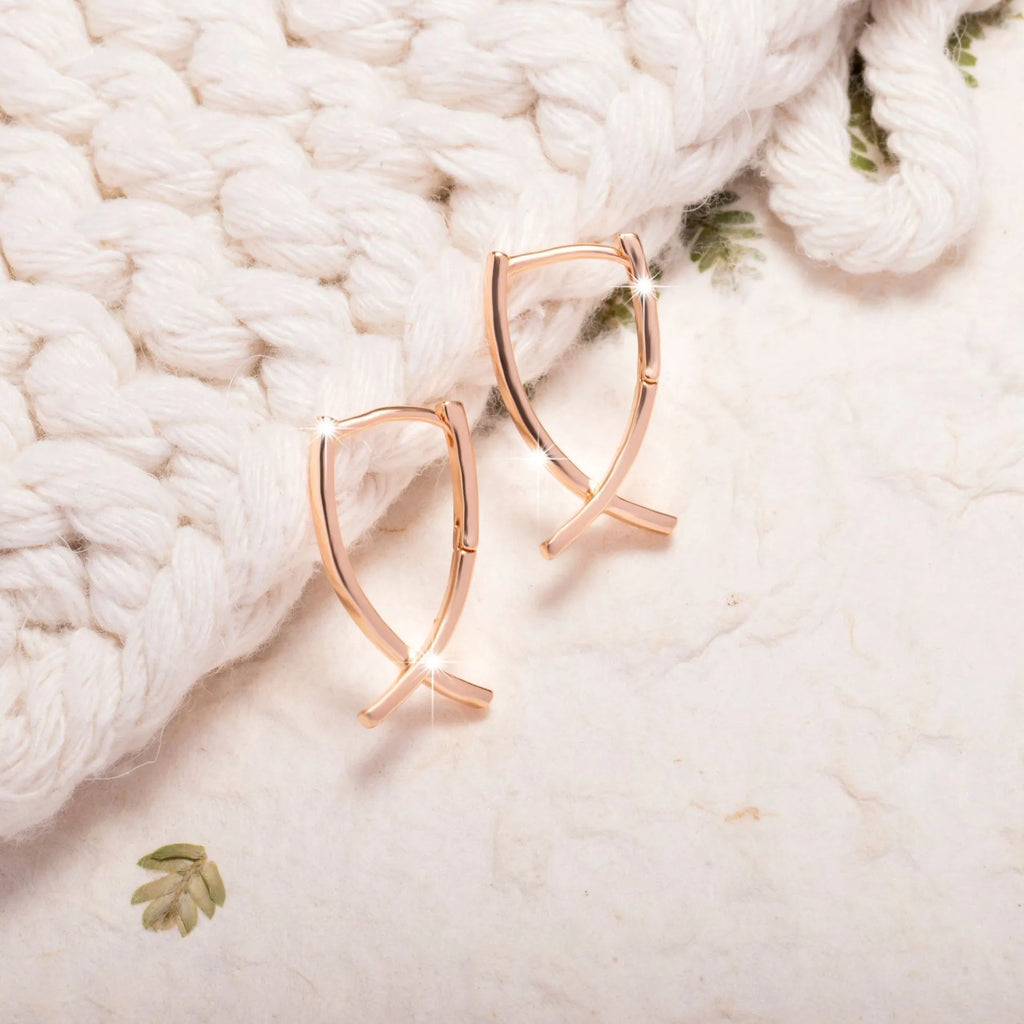 A pair of rose gold cross shaped fashion earrings on a copper alloy base.