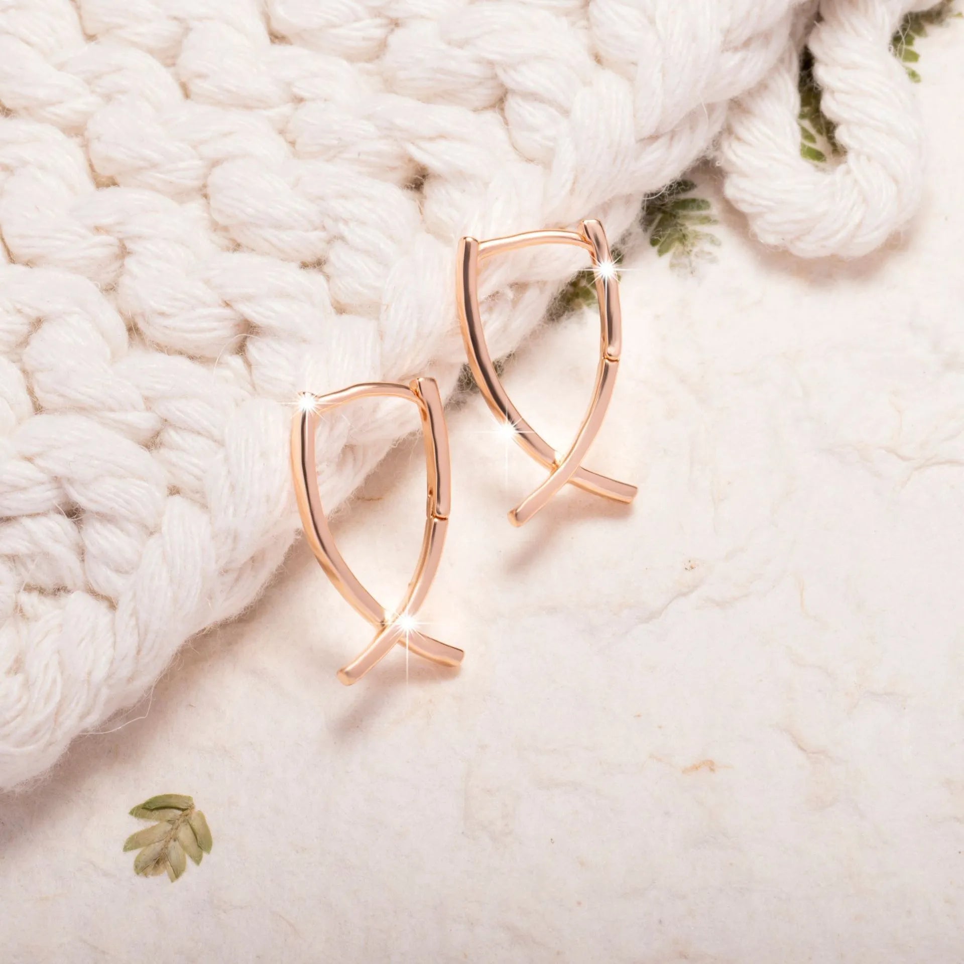 A pair of rose gold cross shaped fashion earrings on a copper alloy base.