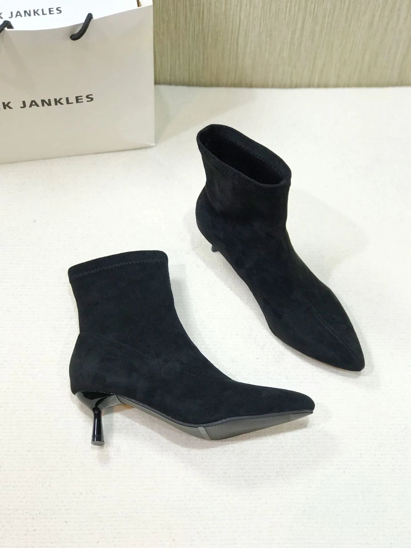 Women's black pointed toe ankle boots with a stiletto heel and mid-calf sock length.