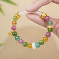 Rainbow coloured electroplated tourmaline half bracelet for women on a wrist.