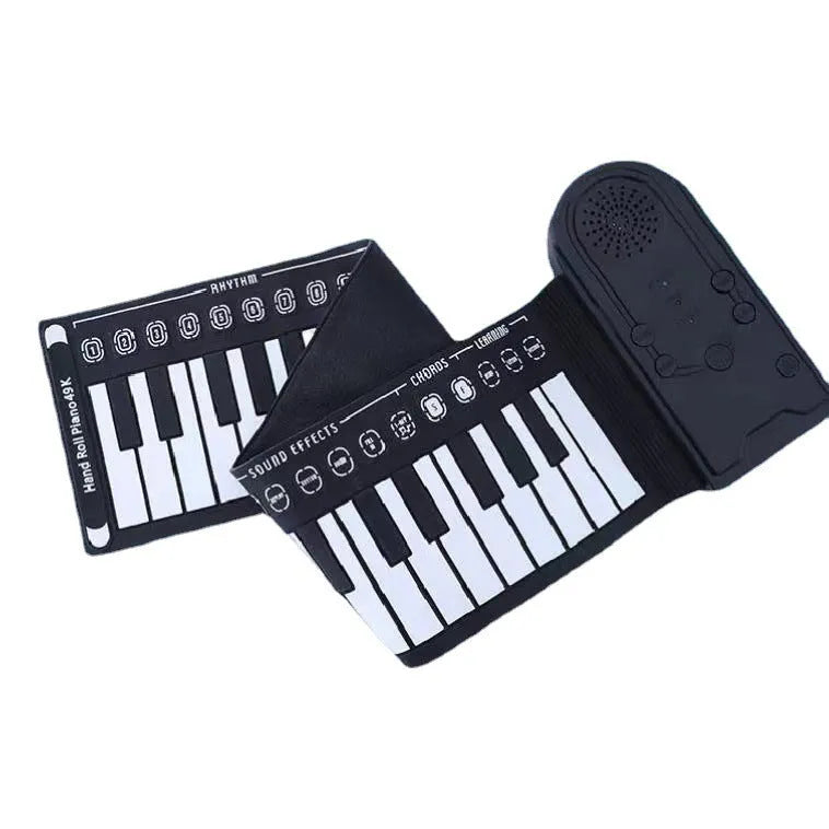 Rolled-up silicone keyboard next to black ABS control unit and speaker for portable 49-key electronic piano.