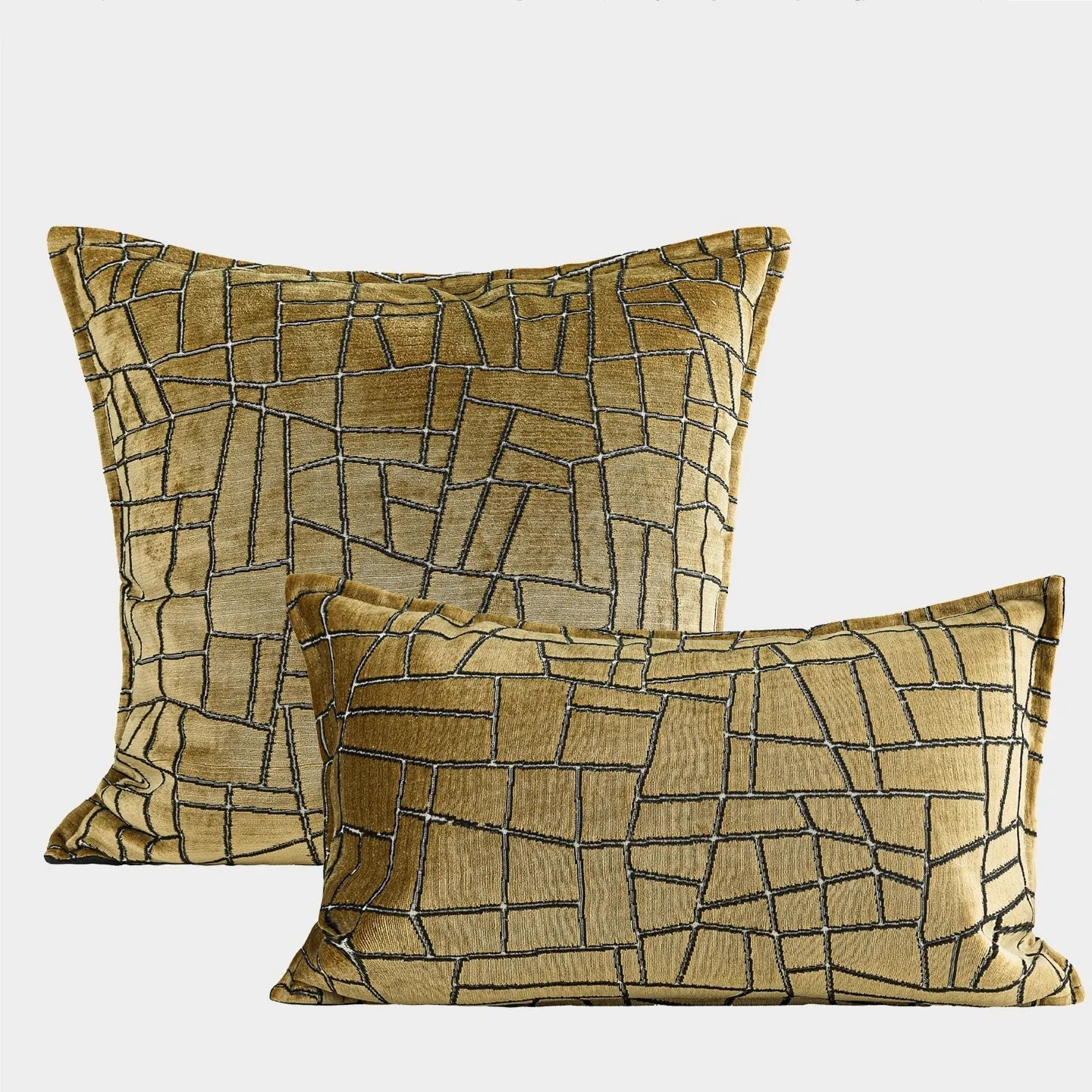 Gold geometric pattern on a velvet square cushion and a rectangular waist pillow against a sofa.
