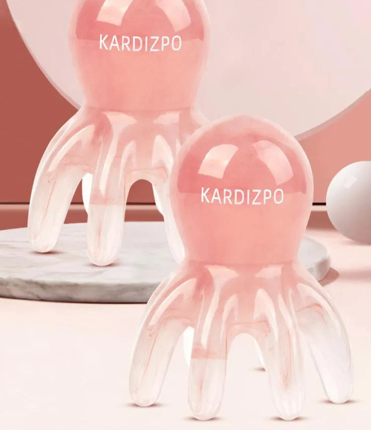 Pink octopus-shaped natural resin massage comb for facial and head massage on a plain background.