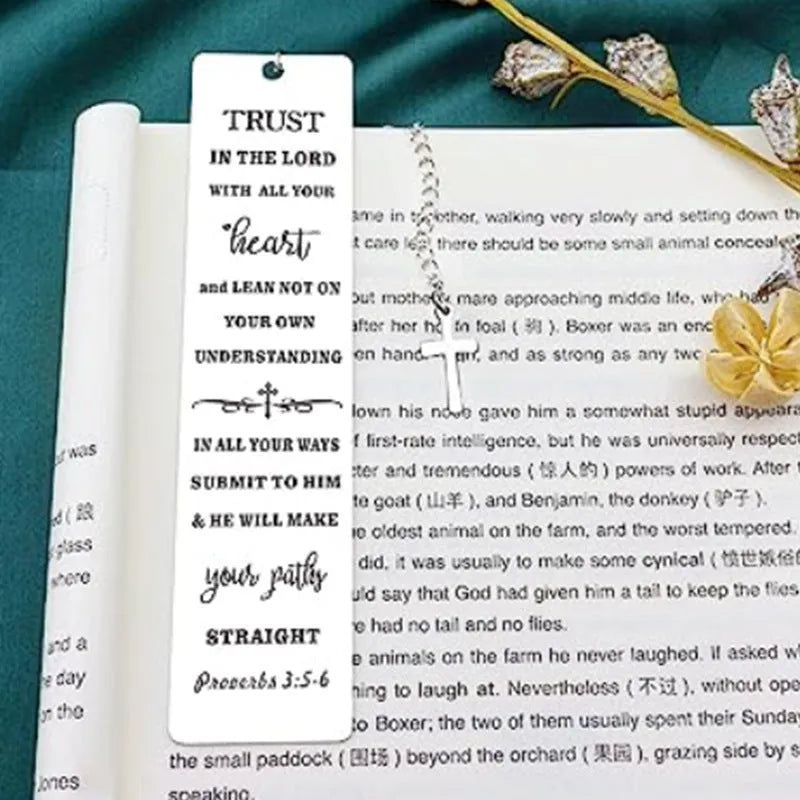 A polished stainless steel bookmark with an engraved inspirational verse, shown against an open book.