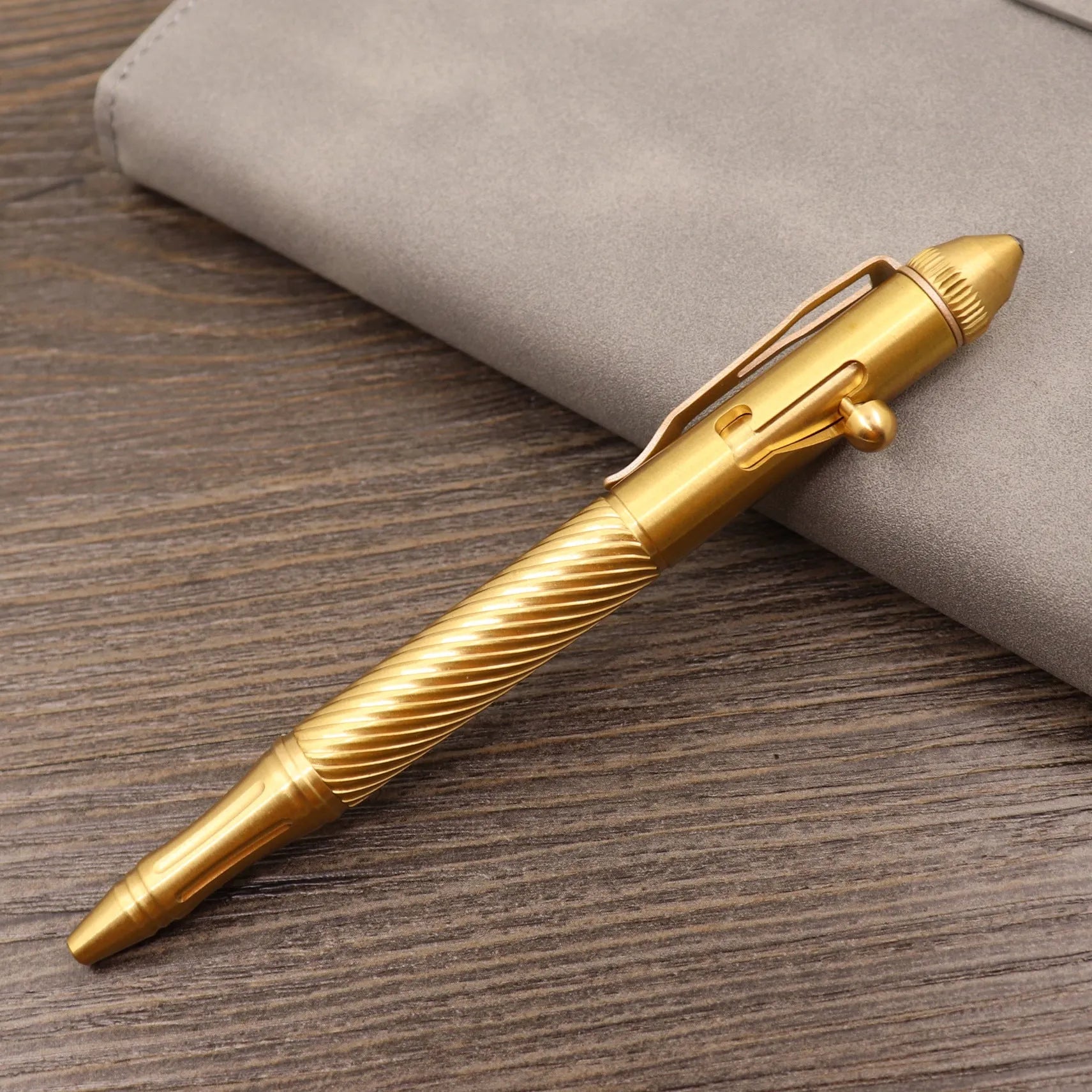 Brass bolt-action tactical pen in a retro copper finish, showing press mechanism and textured barrel.