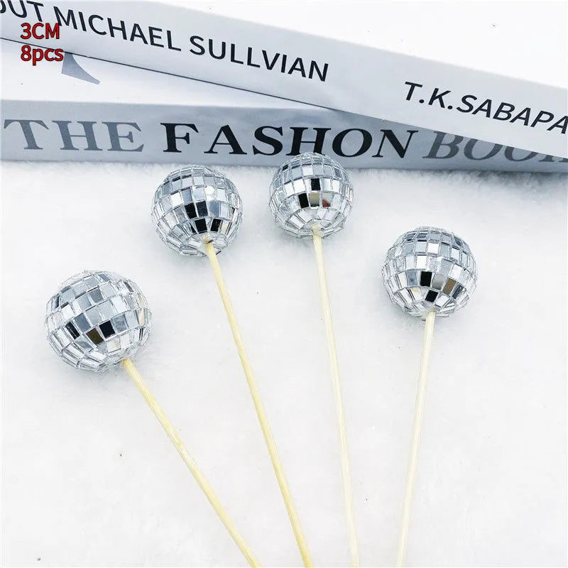 Glass disco ball cake decorations with wooden sticks in multiple sizes on birthday cake