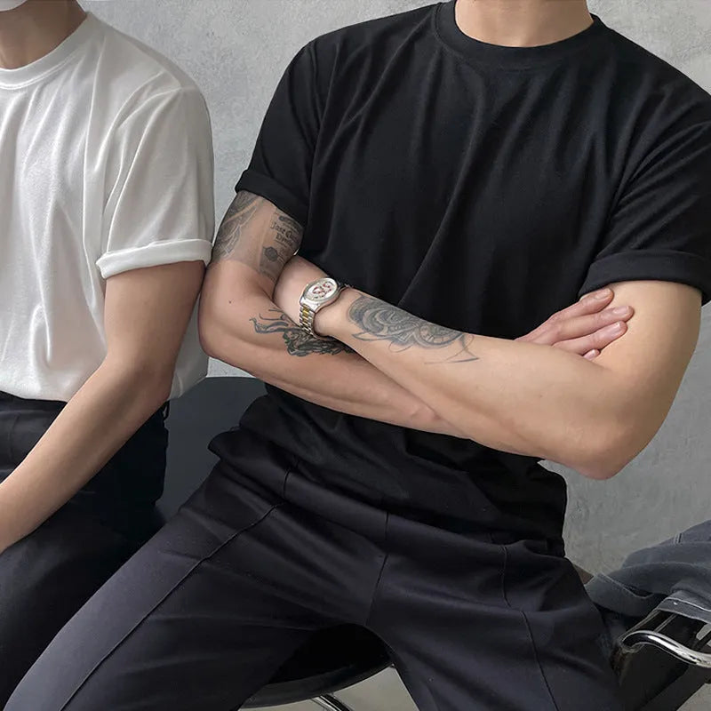 A man wearing a slim fit black cotton T-shirt with a round neck and half sleeves.