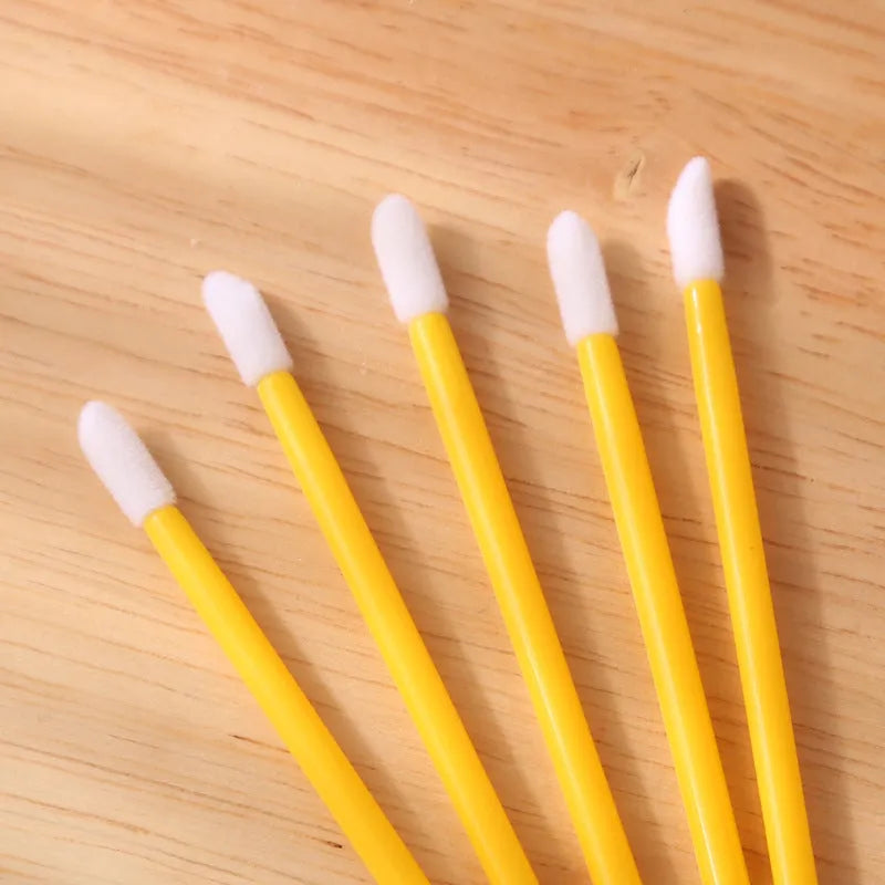 Pack of disposable lip brush applicators with flocked heads and black handles on a white background.