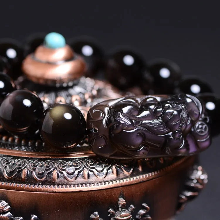 Natural icy obsidian crystal Pi Xiu bracelet with geometric beads on a white background.