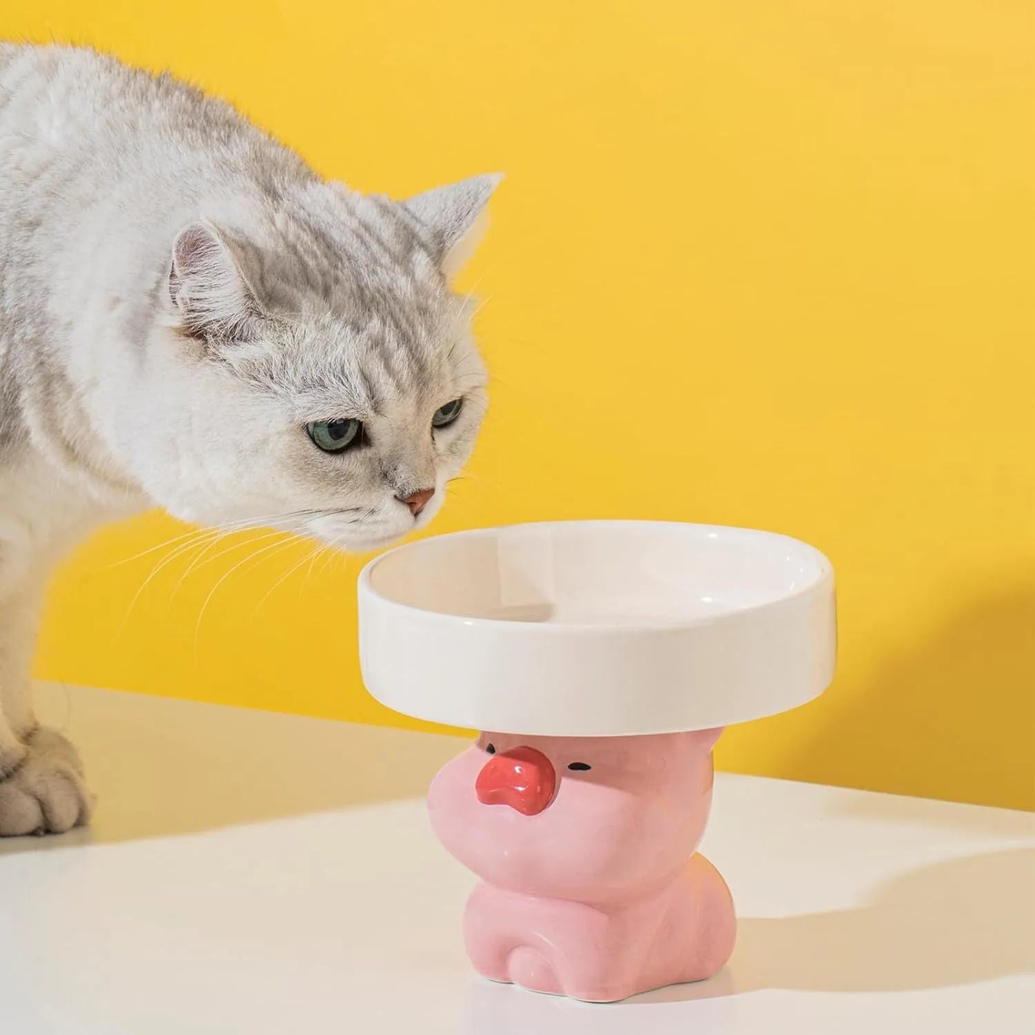 White ceramic raised cat bowl with bear design, showing wide opening and elevated base.