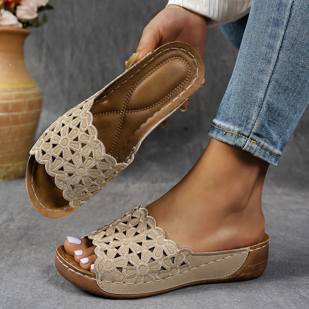 Women's black wedge beach slipper with floral cutouts and fish mouth toe shape on a rubber sole.