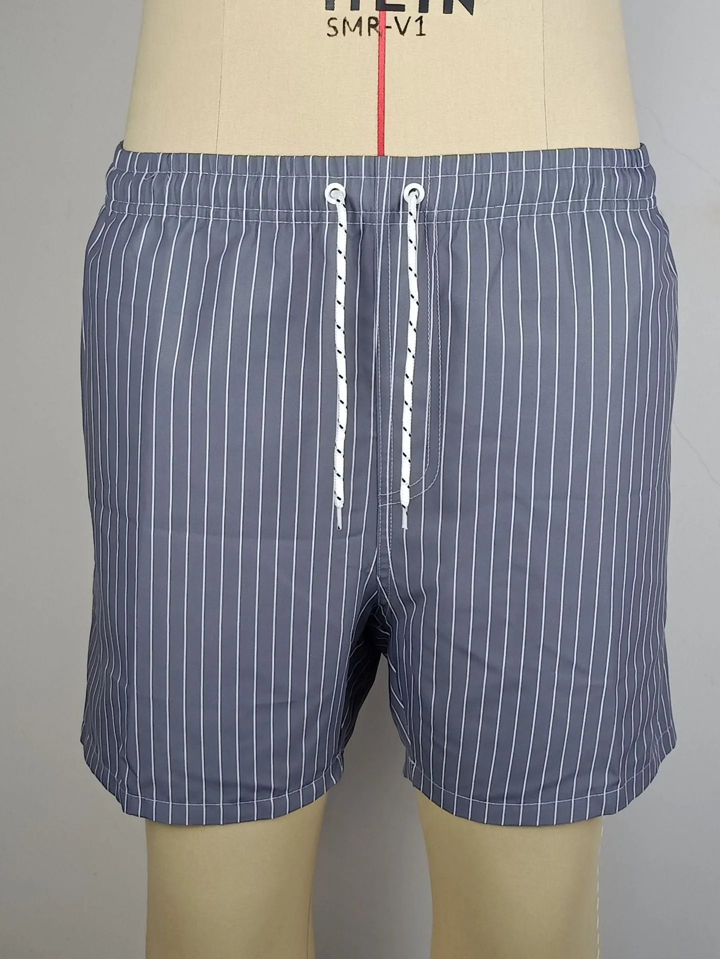 Navy blue and grey striped beach shorts with a straight leg opening on a mannequin.