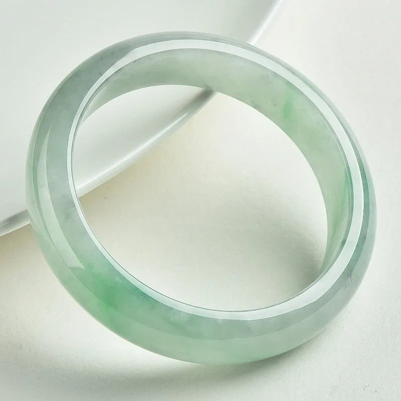 A light green jade bracelet for men and women, shown on a wrist, with a natural stone texture.