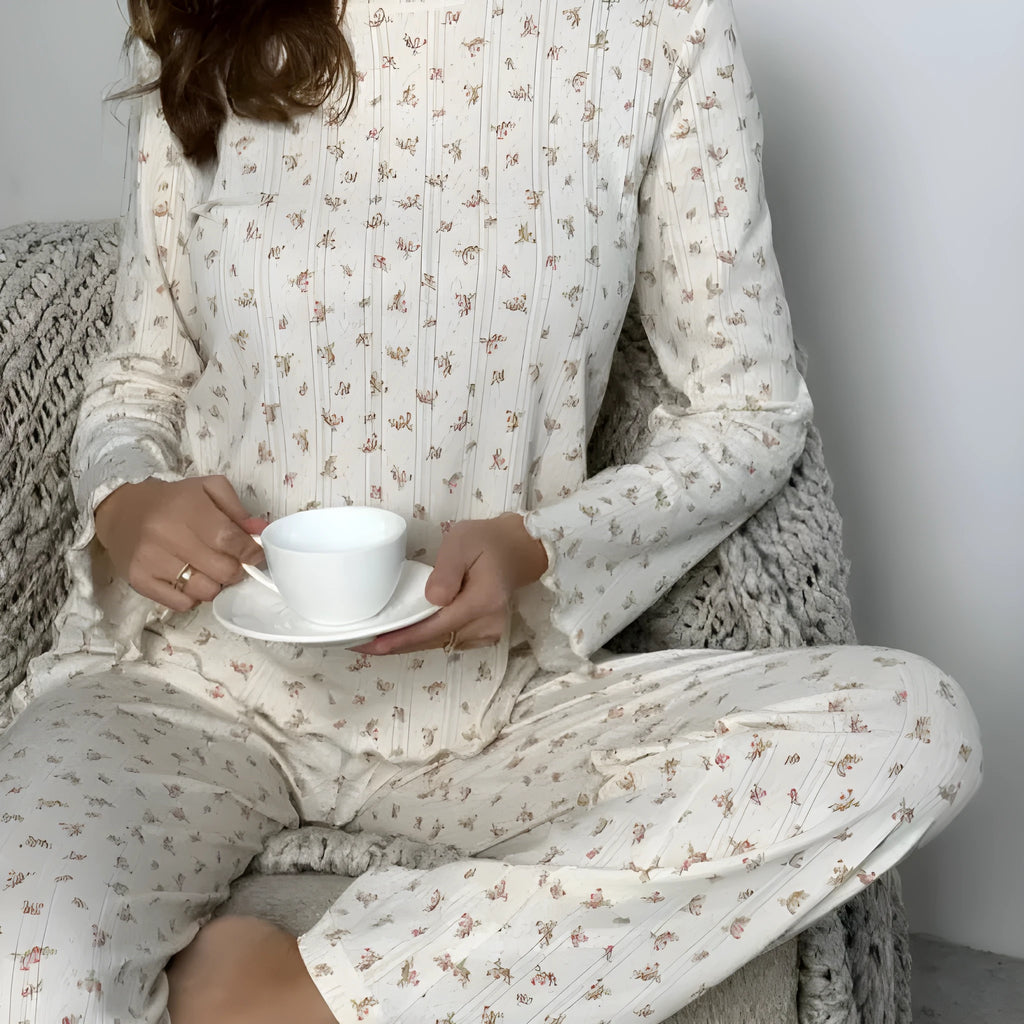 White women's floral print two-piece suit with bell sleeve top and wide leg pants on a hanger.