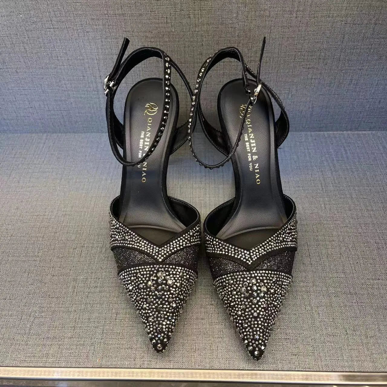 Women's silver high heel shoe with hollow stiletto heel, pointed toe, and bright red sole.