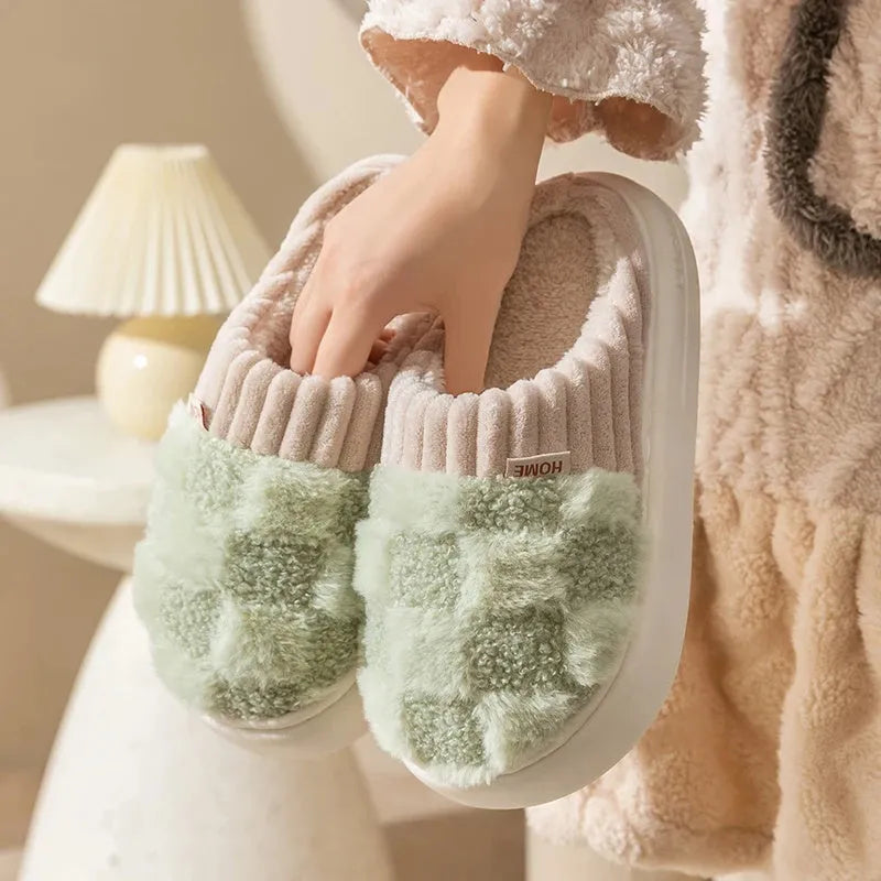 Women's plaid patterned coral velvet indoor slippers with a thick soft sole on a wooden floor.