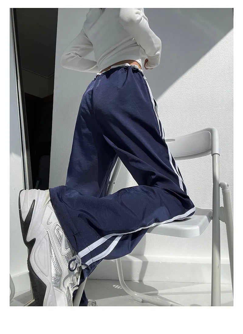 Women's navy blue loose straight-leg pants with white contrast ribbon parallel bars detail and low waist.