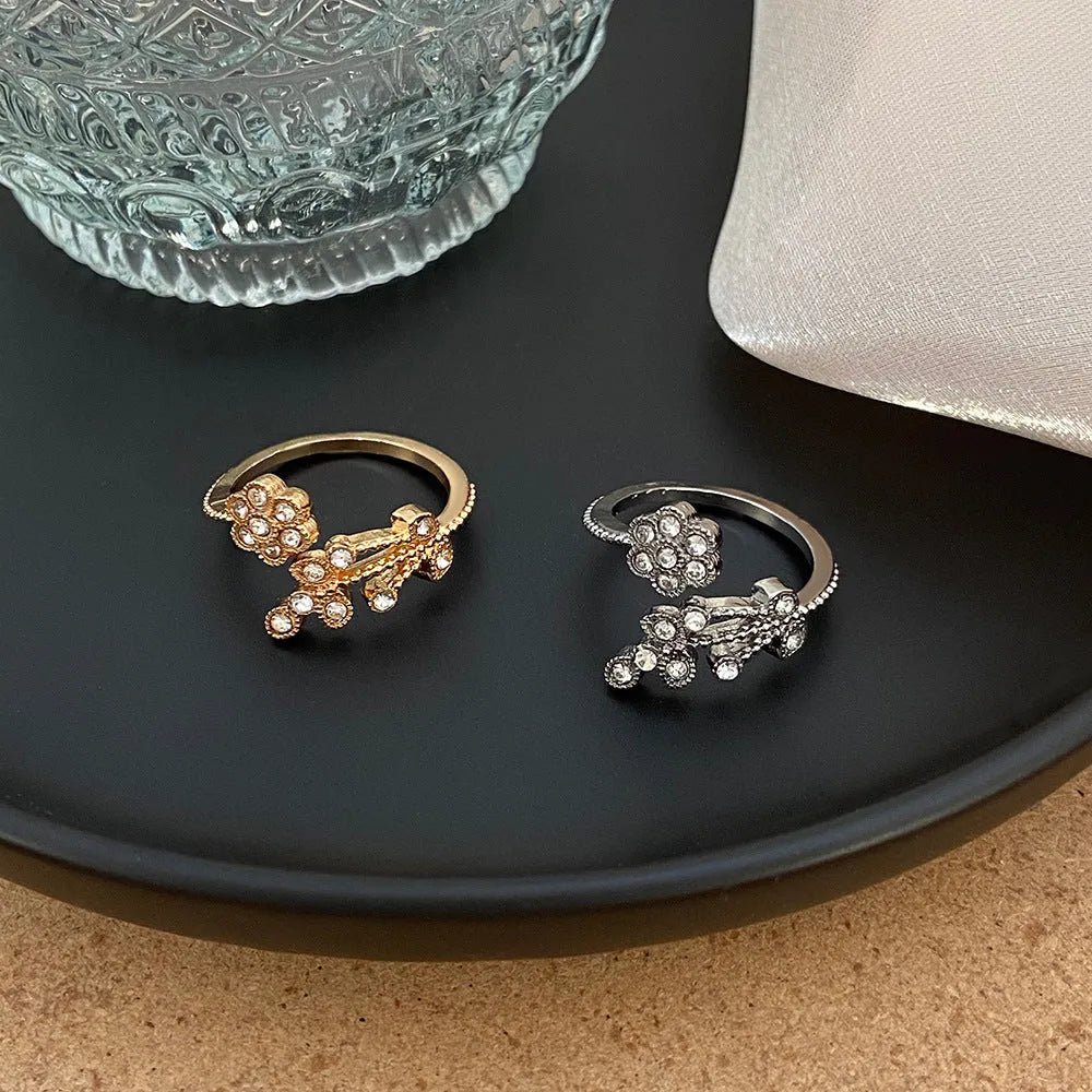 Women's open ring made of copper with a diamond finish, shaped as a detailed flower with leaves, shown in gold and white colour options.