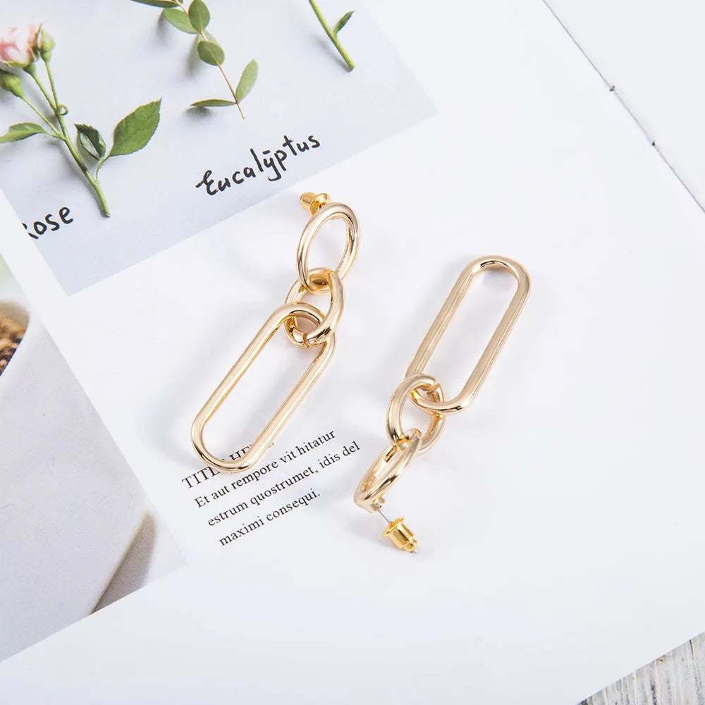 Geometric sterling silver needle hoop earrings with ring and line design on a white background.