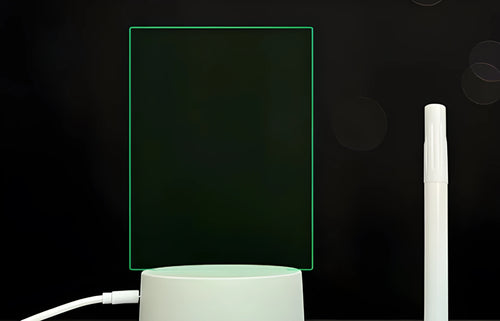 Black 3D acrylic message board LED light with remote control and marker pen on a desk.