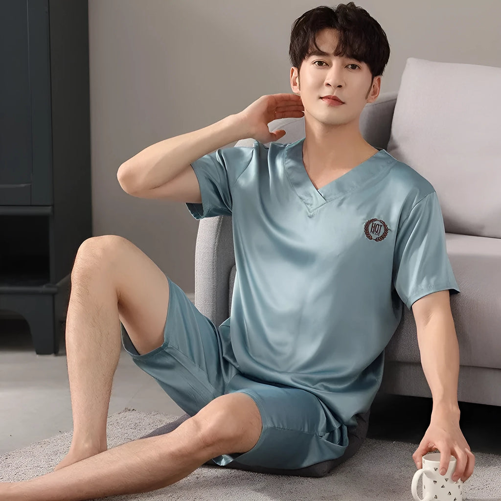 Man wearing a loose light blue short-sleeve pyjama shirt and matching shorts, illustrating the ice silk sleepwear set.