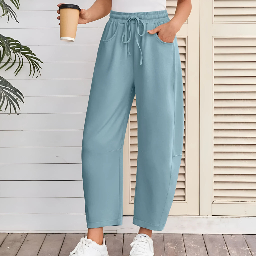 Women's loose grey cropped sweatpants with drawstring waist and side pockets on a hanger.