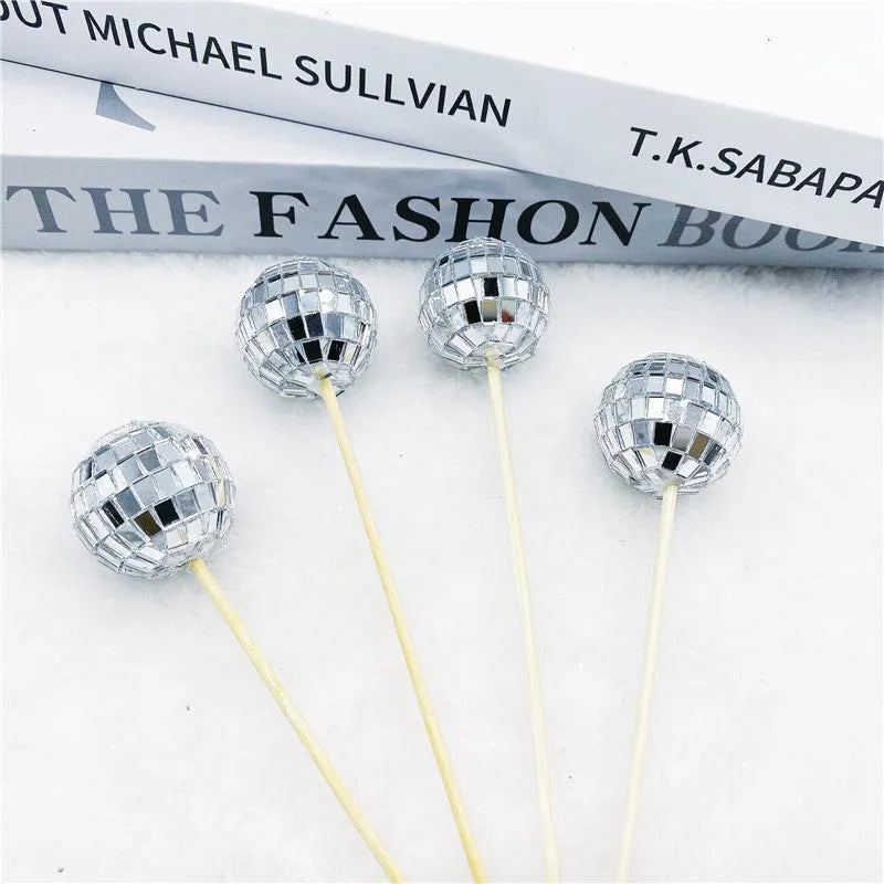 Glass disco ball cake decorations with wooden sticks in multiple sizes on birthday cake