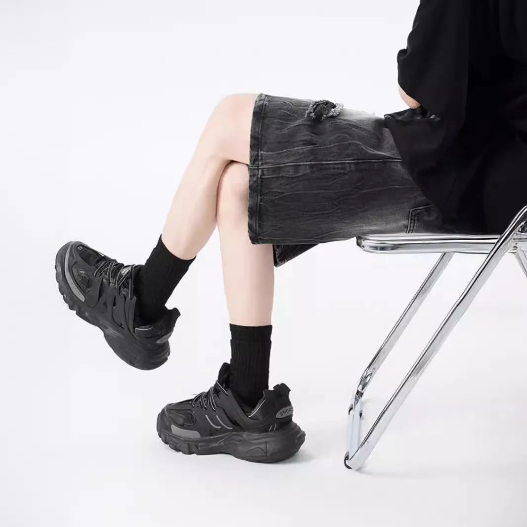 Washed black denim shorts with ripped details and loose retro fit showing front view