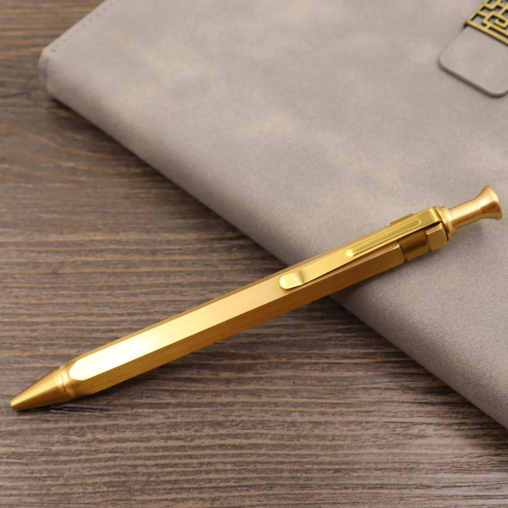 Brass bolt-action tactical pen in a retro copper finish, showing press mechanism and textured barrel.