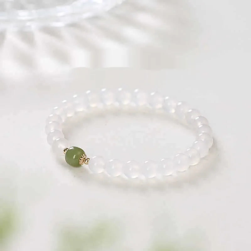 Handmade white agate and crystal bracelet with red cinnabar inlay on a wrist.