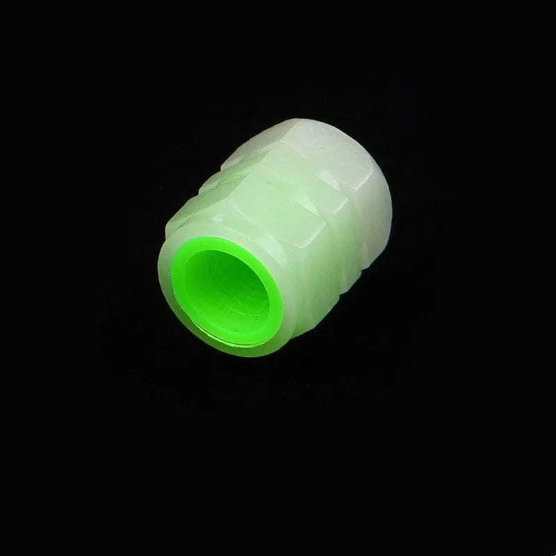 Set of four luminous rubber car valve caps glowing on a dark background.