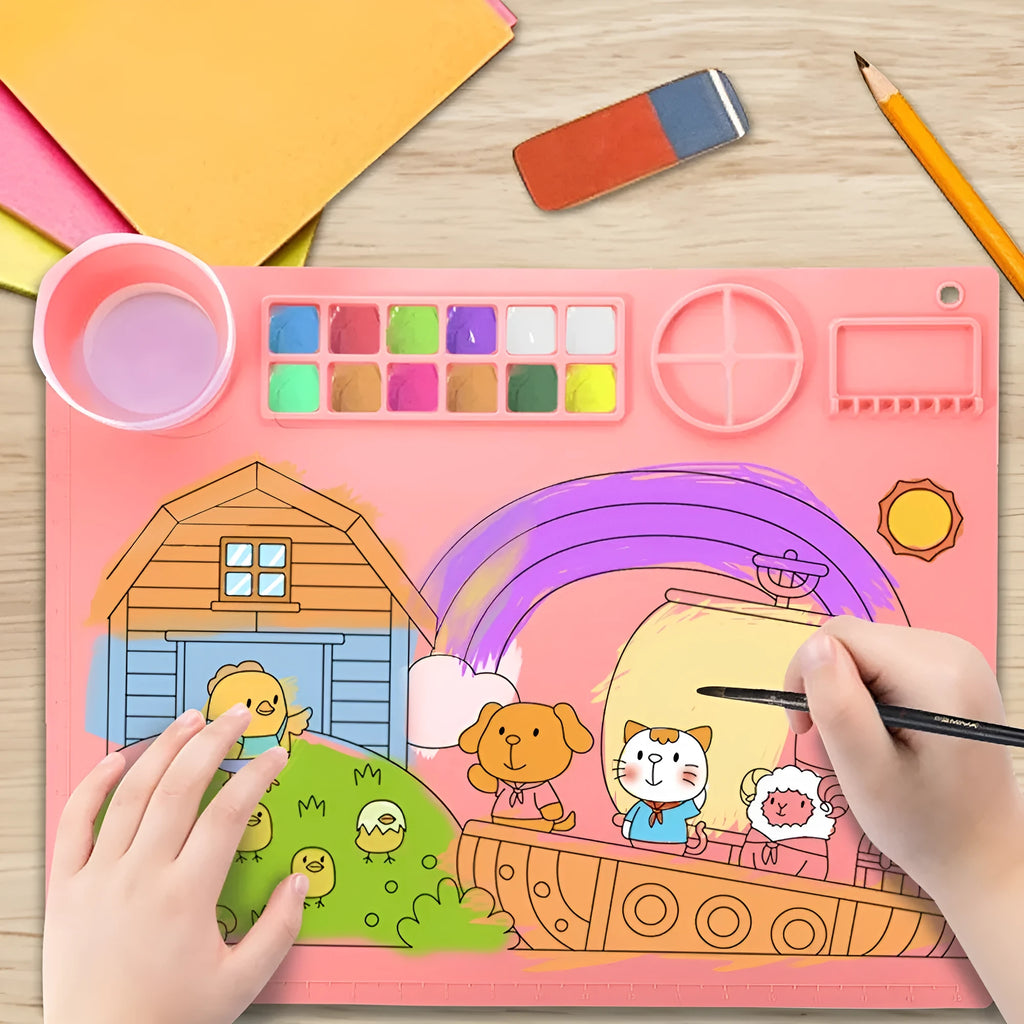 Light blue silicone painting mat with an integrated bowl on one side, positioned on a wooden table.