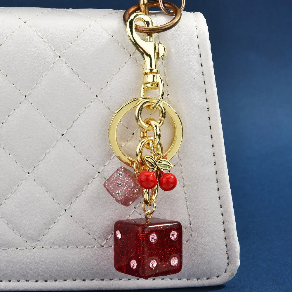 Square metal keychain pendant with a cerise two-tone dice pattern.