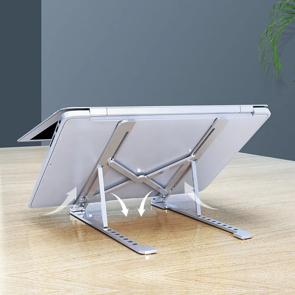 A folded silver aluminium laptop stand next to an open laptop, showing its thin profile and adjustable angle mechanism.