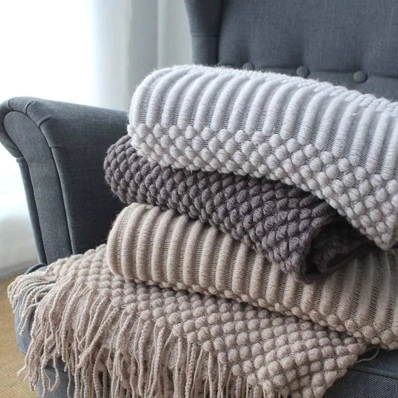 Small grey polyester nap blanket folded on a sofa, showing its texture and size.