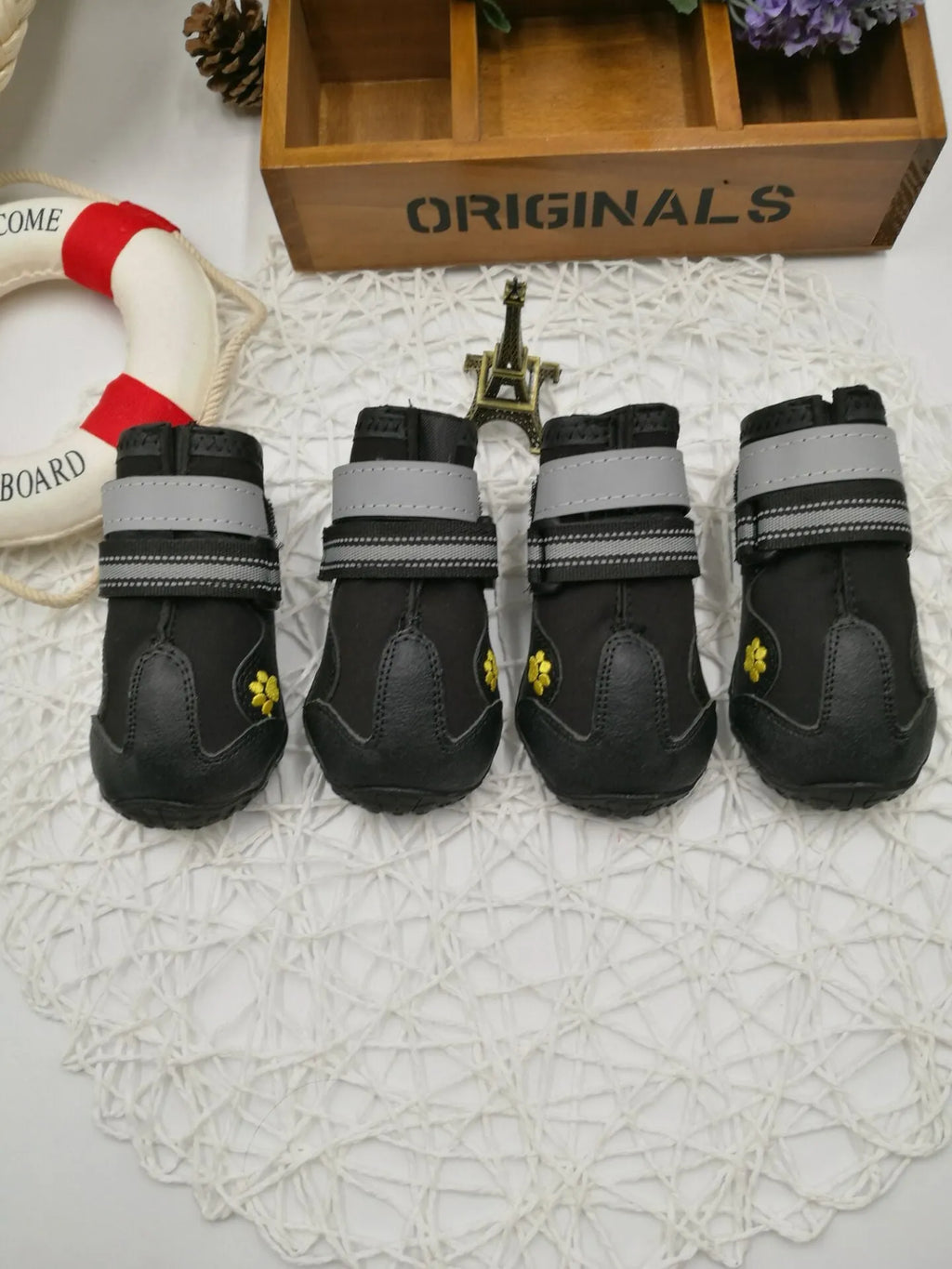 Black dog shoes with waterproof PVC sole and adjustable fuzzy belt on a dog's paw