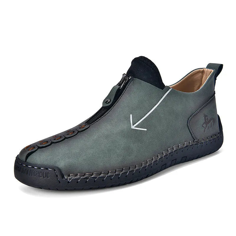 Men's black leather boots with a front zipper and round toe, showing hand-stitched sole detail.