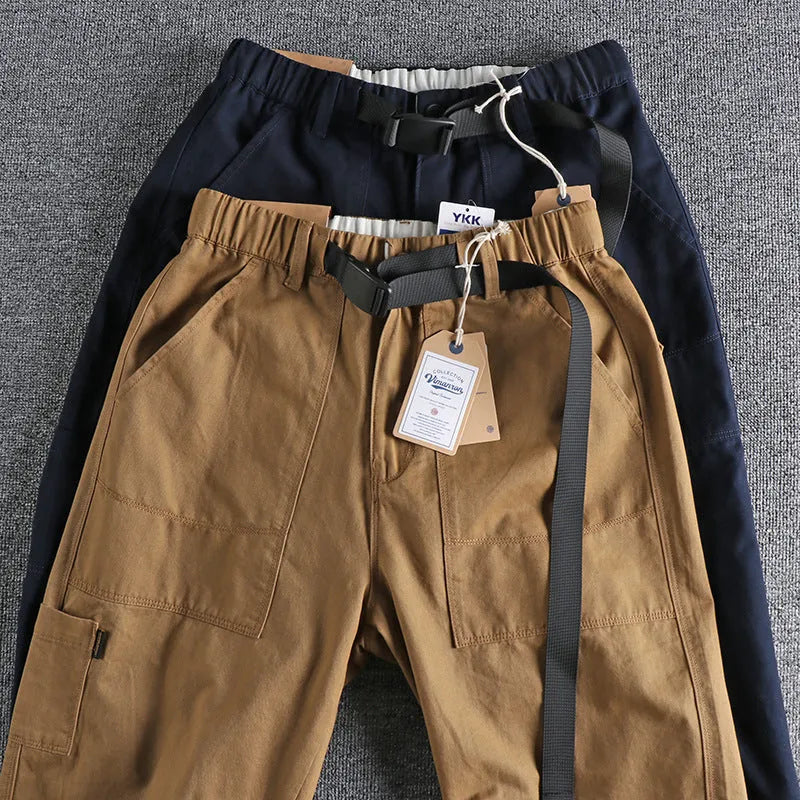 Men's khaki cotton work trousers with three-dimensional cutting and a silver N I buckle belt on the waist.