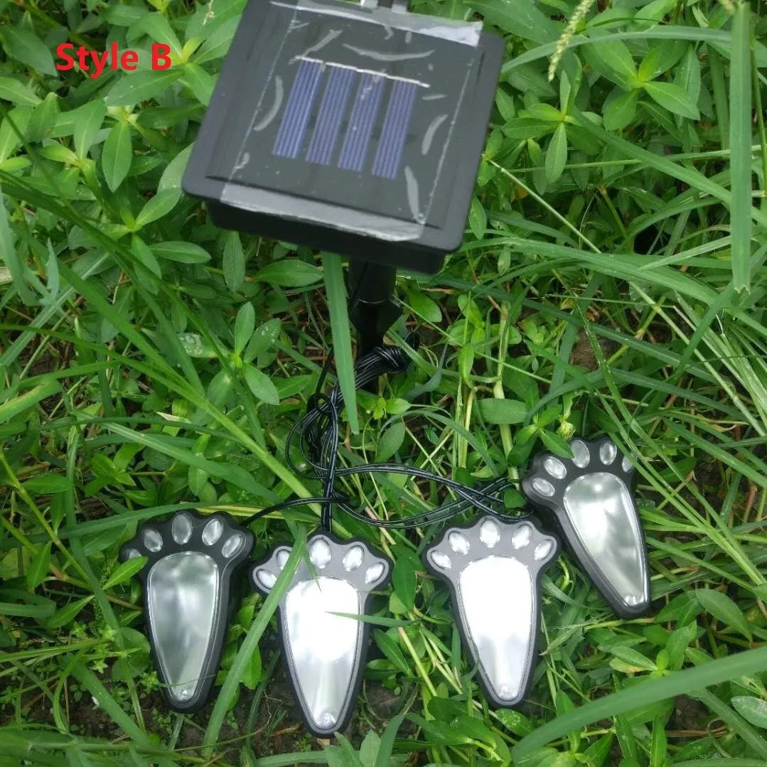 Set of four black bear paw print solar LED garden lights with a central solar panel pole on grass.