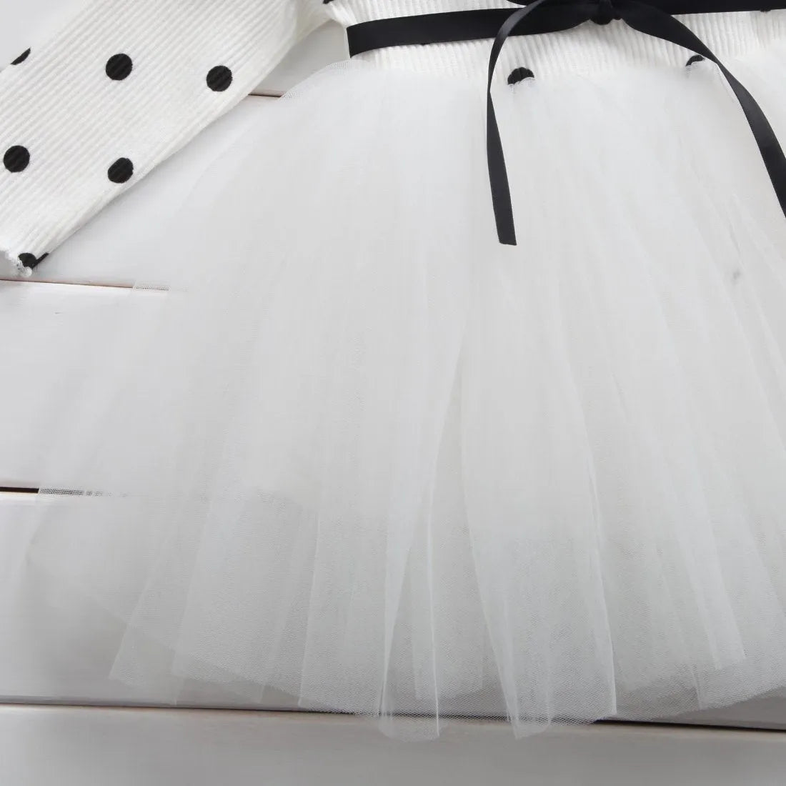 Baby girl wearing a long sleeve black lace tutu dress for a christening or birthday party.