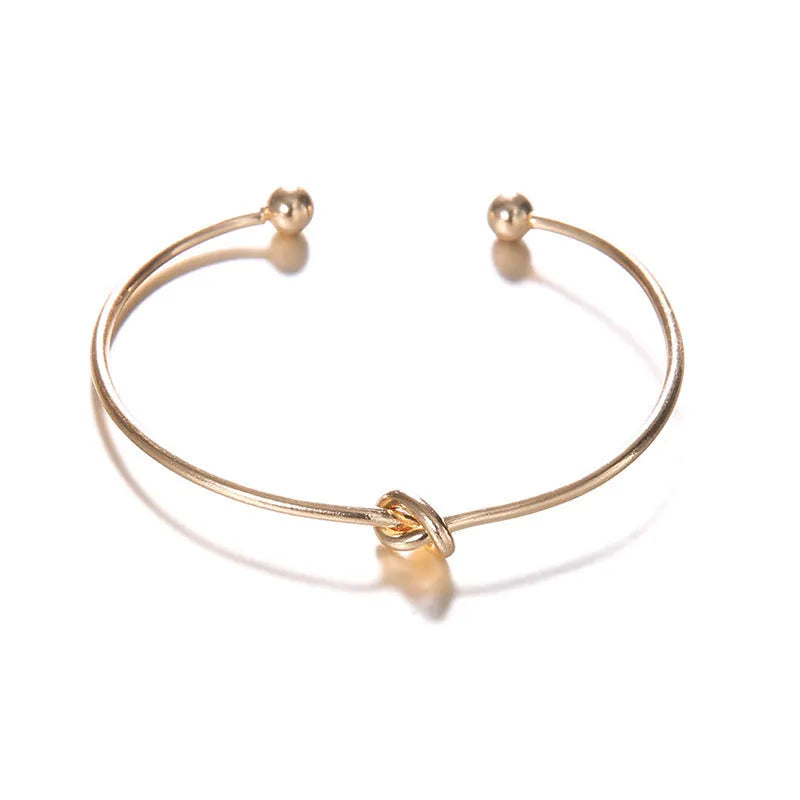 Gold-coloured women's vintage cuff bracelet with an arrow knot detail on an alloy band.