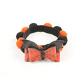 Halloween pet collar with a furry ball accessory in a pumpkin design on a dog's neck.