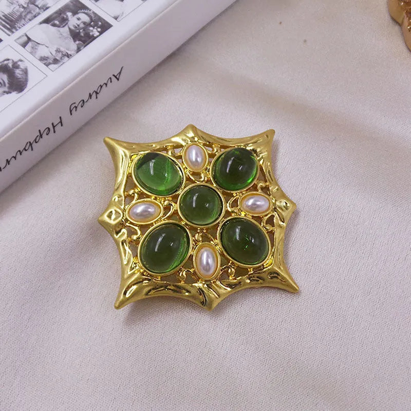 Close-up of a detailed baroque cross brooch with crystal accents on a zinc alloy base.